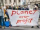 People hold a banner that reads Planet Over Profit